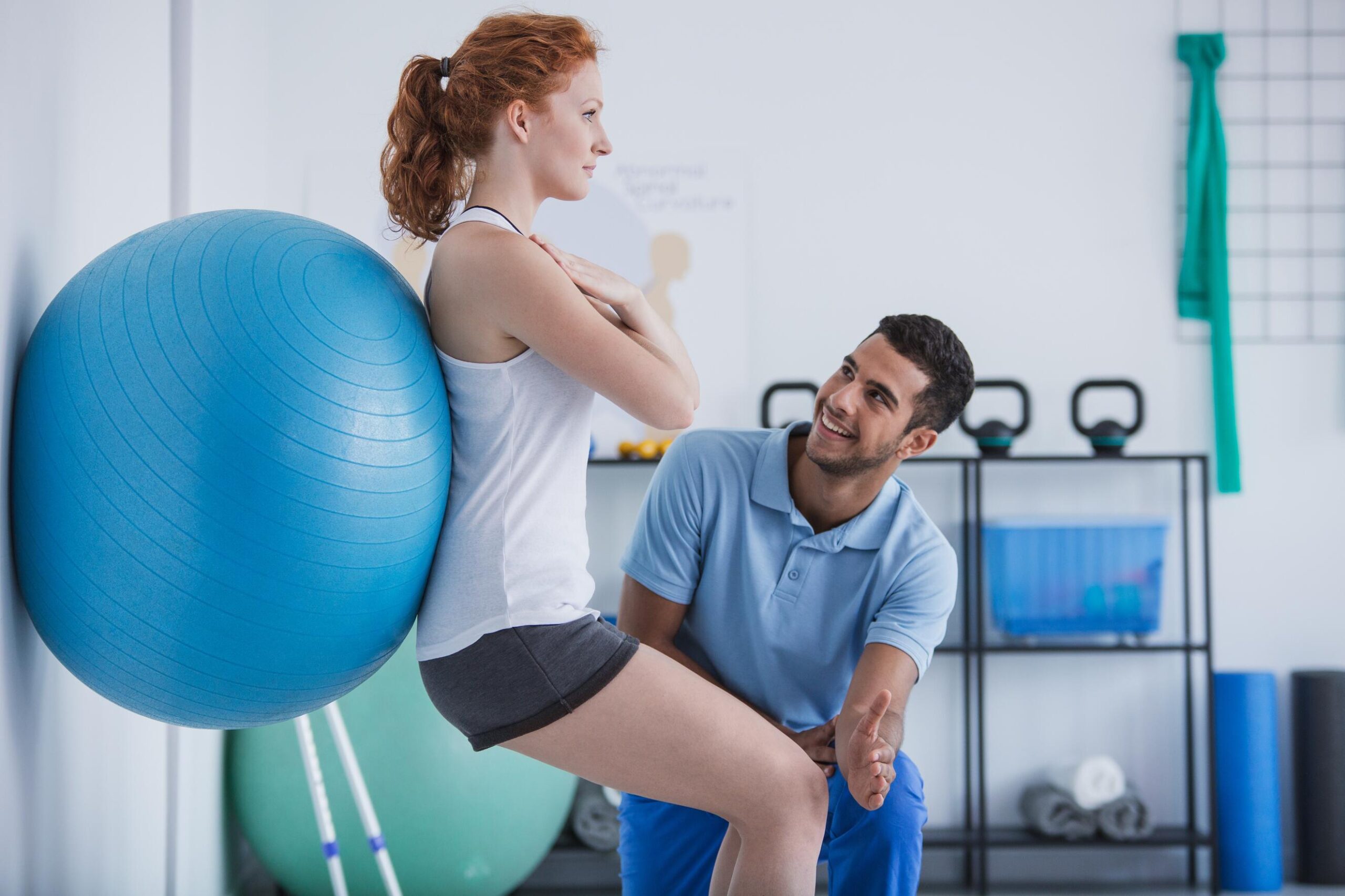 physical therapist guiding woman using an exercise ball assited wall-sit exercises